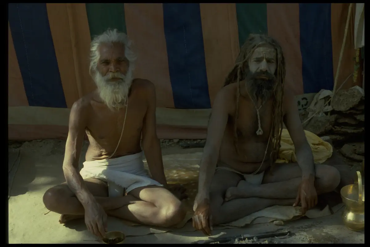 Two sadhus seated striped tent